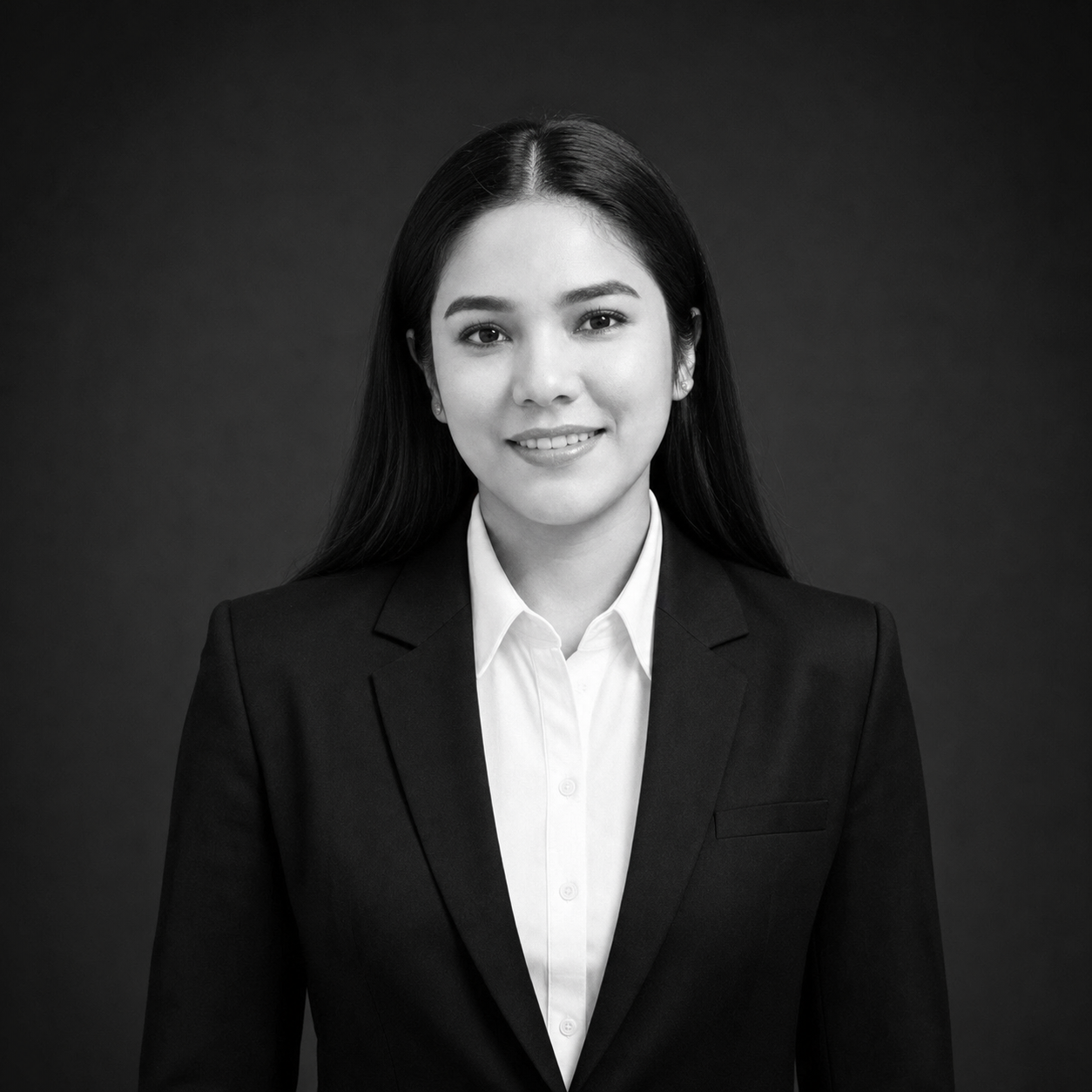 Professional headshot of a smiling woman in a black blazer and white shirt against a dark background.