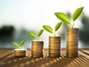 Stacks of coins increasing from left to right with green plant sprouts, symbolizing growing savings or investments.