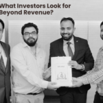 Four men in business attire pose together as one hands a certificate to another, Foxhog logo visible in the background (black and white photo).